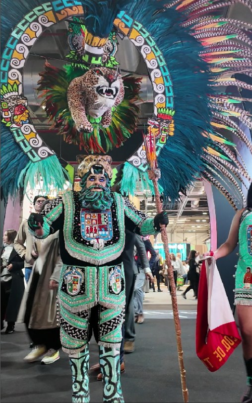 Danzante con penacho de plumas y una bailarina en el estand de México en FITUR